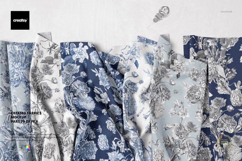 Creased fabric mockup featuring multiple pieces of cloth with blue and gray floral patterns, viewed from above.