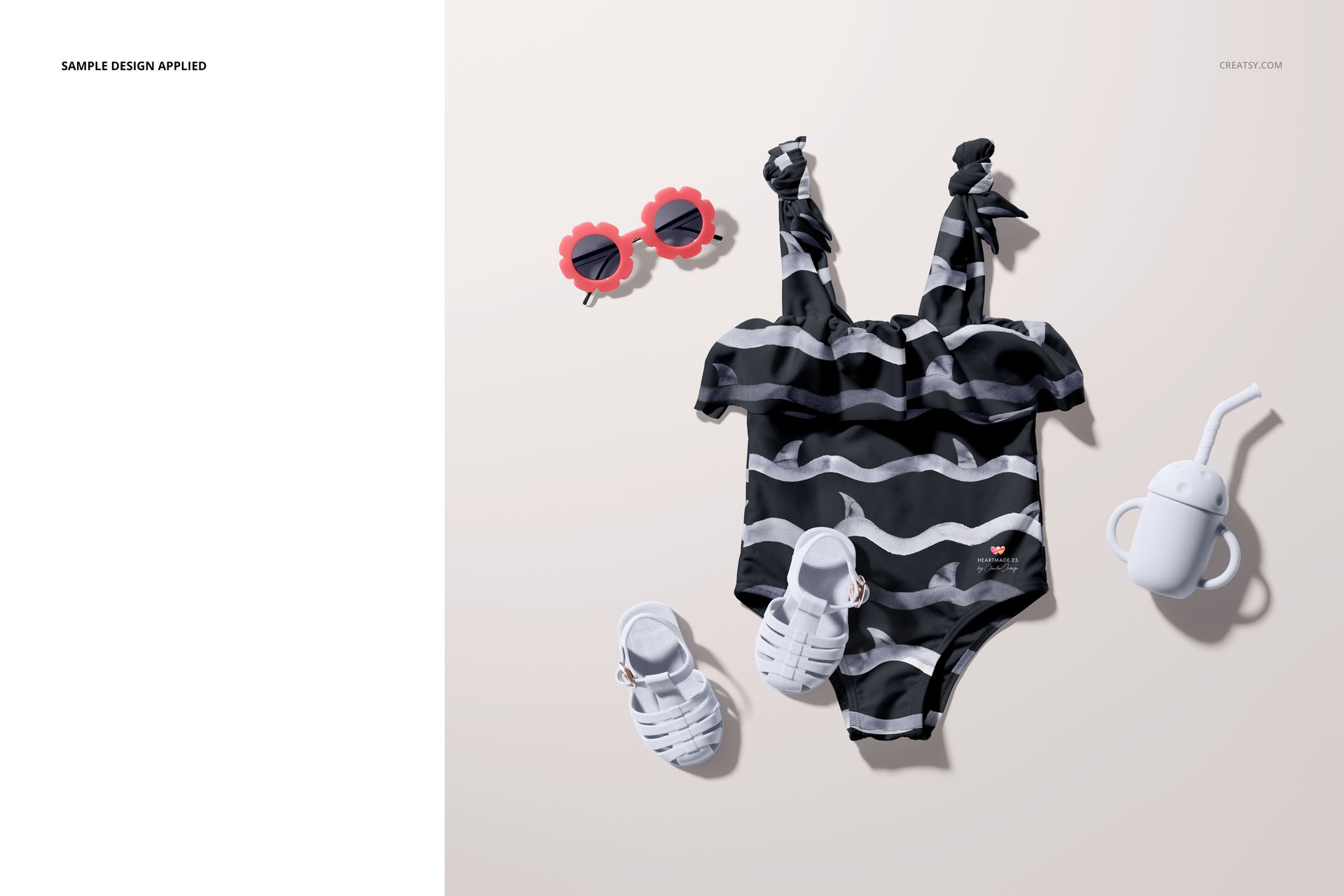 Black and white patterned baby swimsuit mockup displayed with white sandals, red sunglasses, and a white sippy cup.