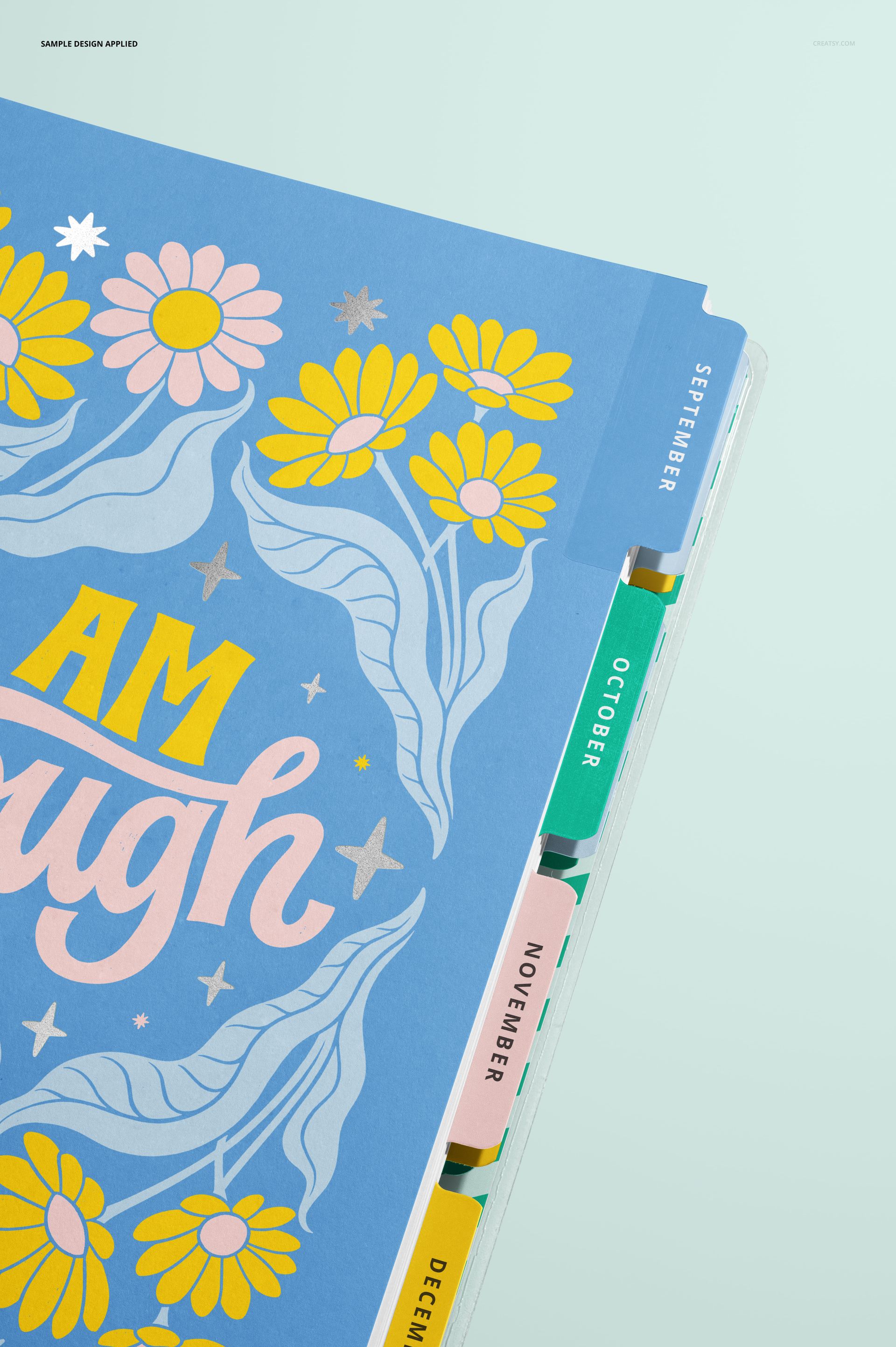 Detailed close-up of a stationery planner mockup showing colorful floral cover and labeled tab dividers for months.