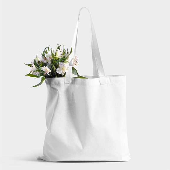 Blank white tote bag photographed with flowers against a light background